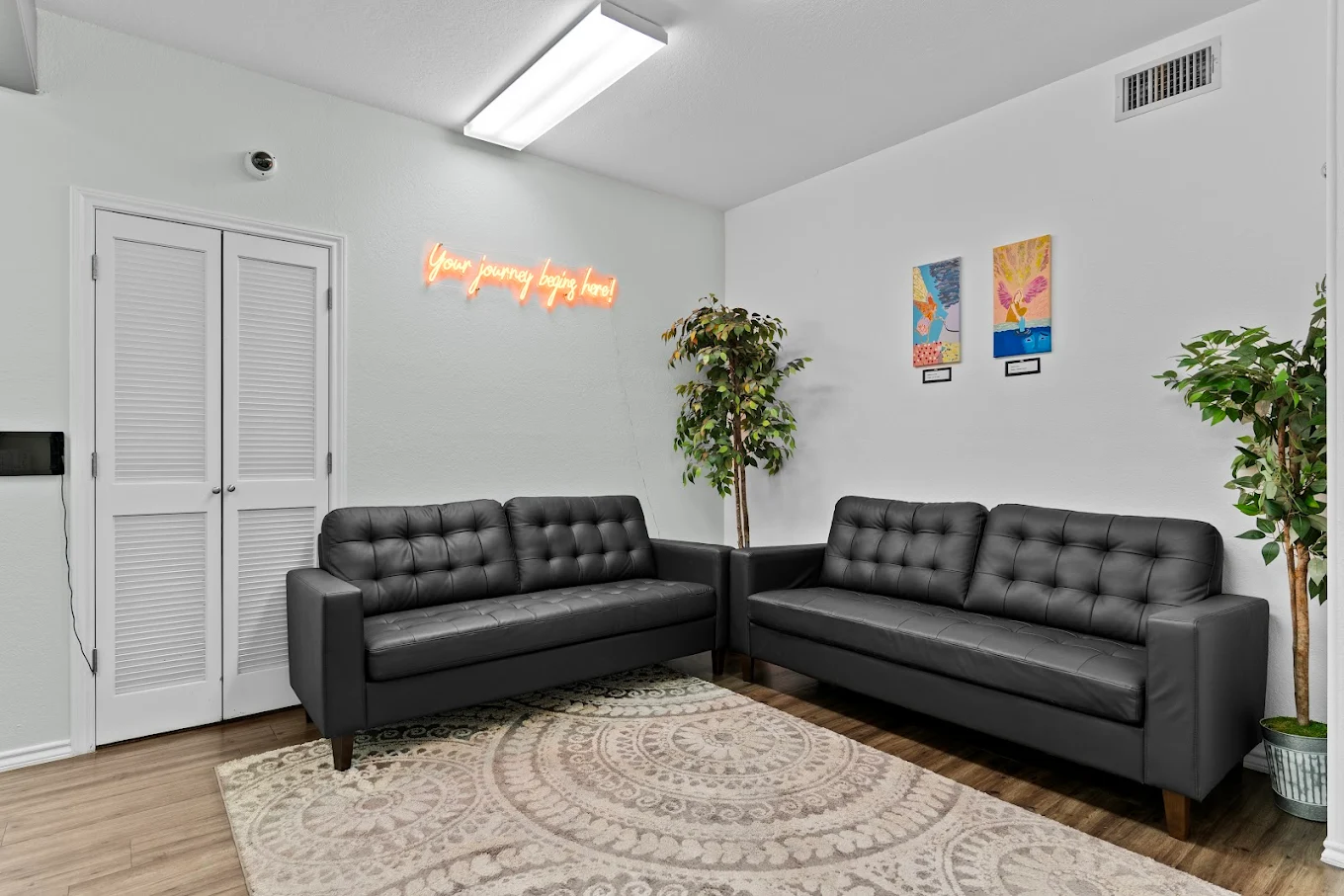 Lounge with black sofas, plants, and inspirational wall sign