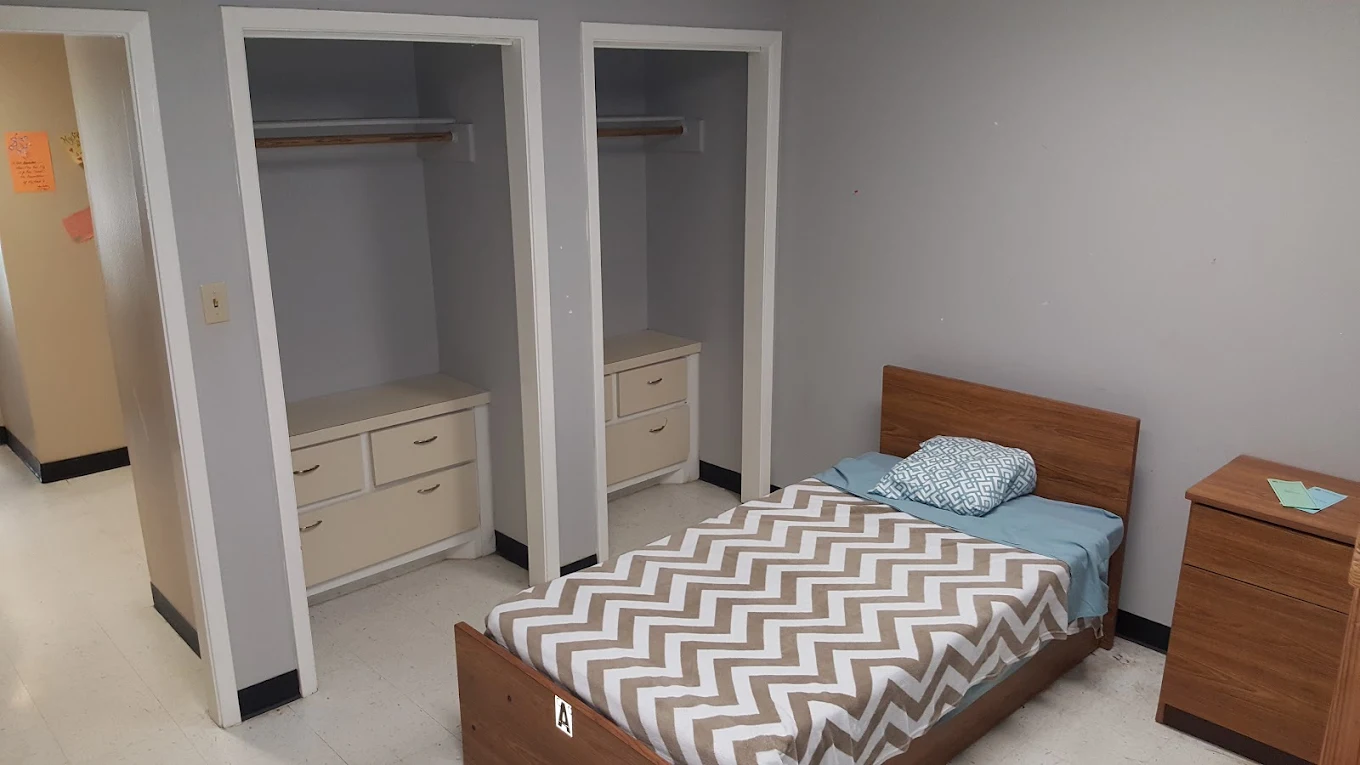 Simple bedroom with single bed and open closet storage.