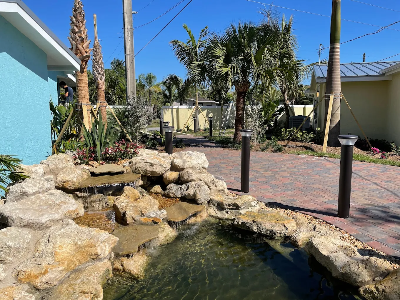 Small rock pond with cascading water near palm trees