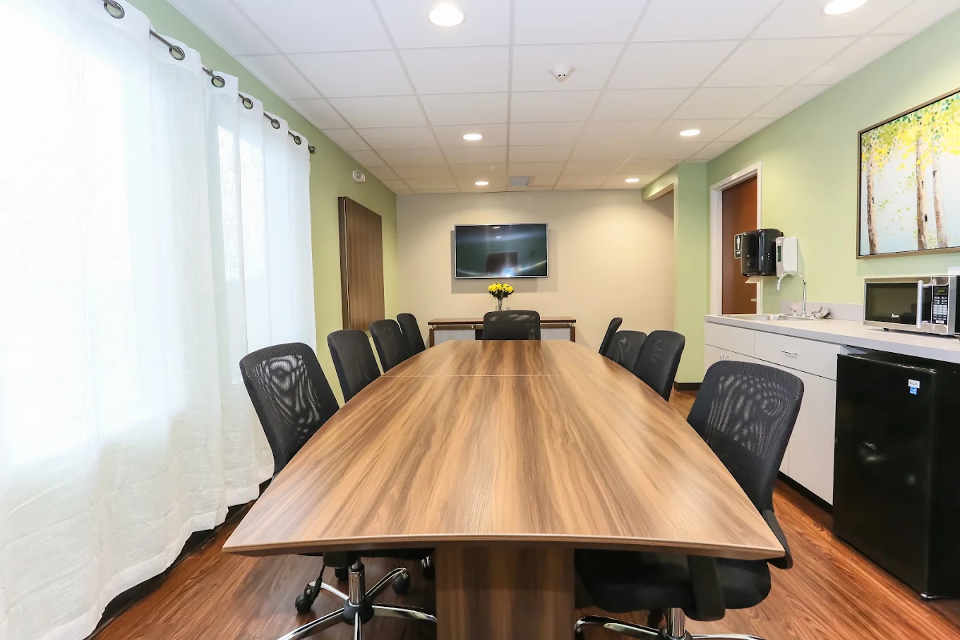 Conference room with a long wooden table and black chairs