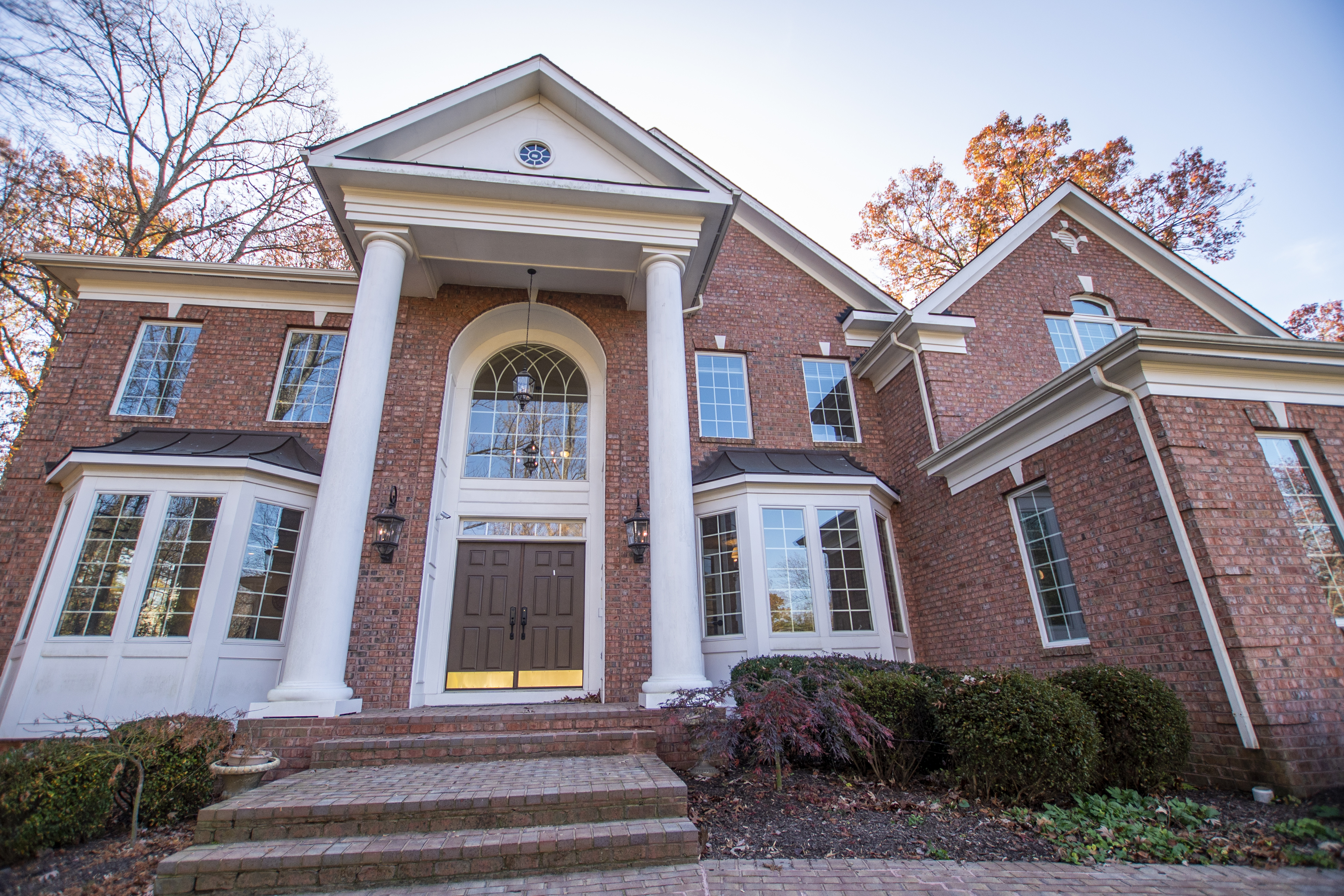 Red-brick facility entrance with white pillars and windows.