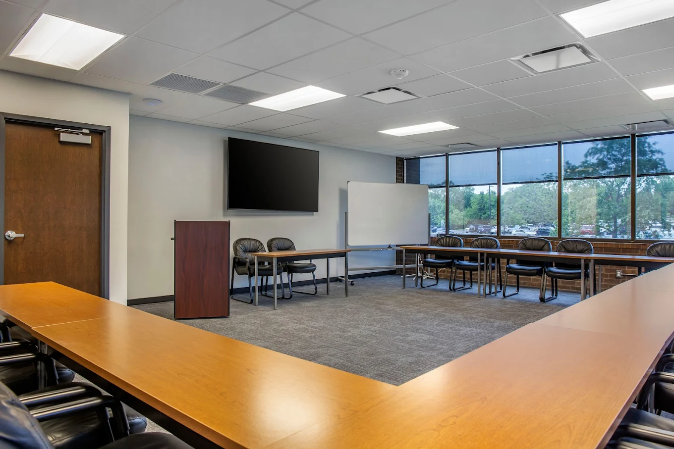 Conference room with tables, chairs, TV, and whiteboard