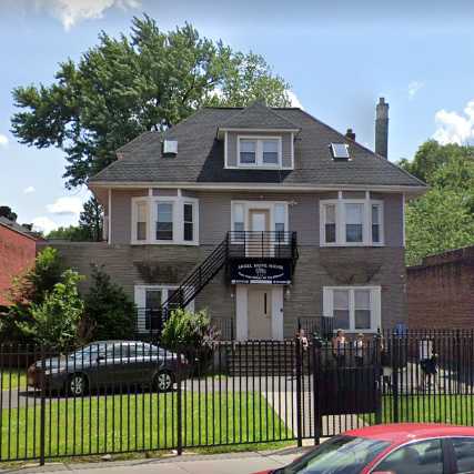 Large house-style building with fenced front lawn and parked cars