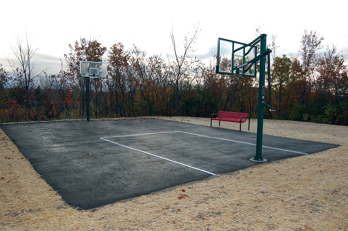 Small blacktop basketball court with two hoops and a bench