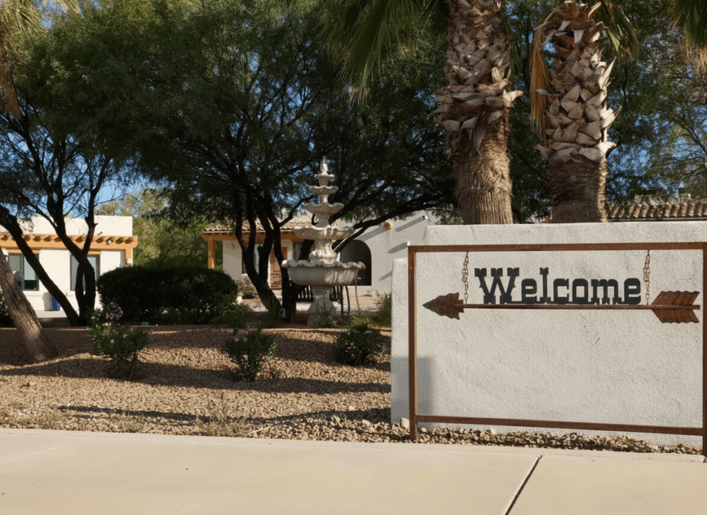 Welcome sign near trees and fountain at facility entrance