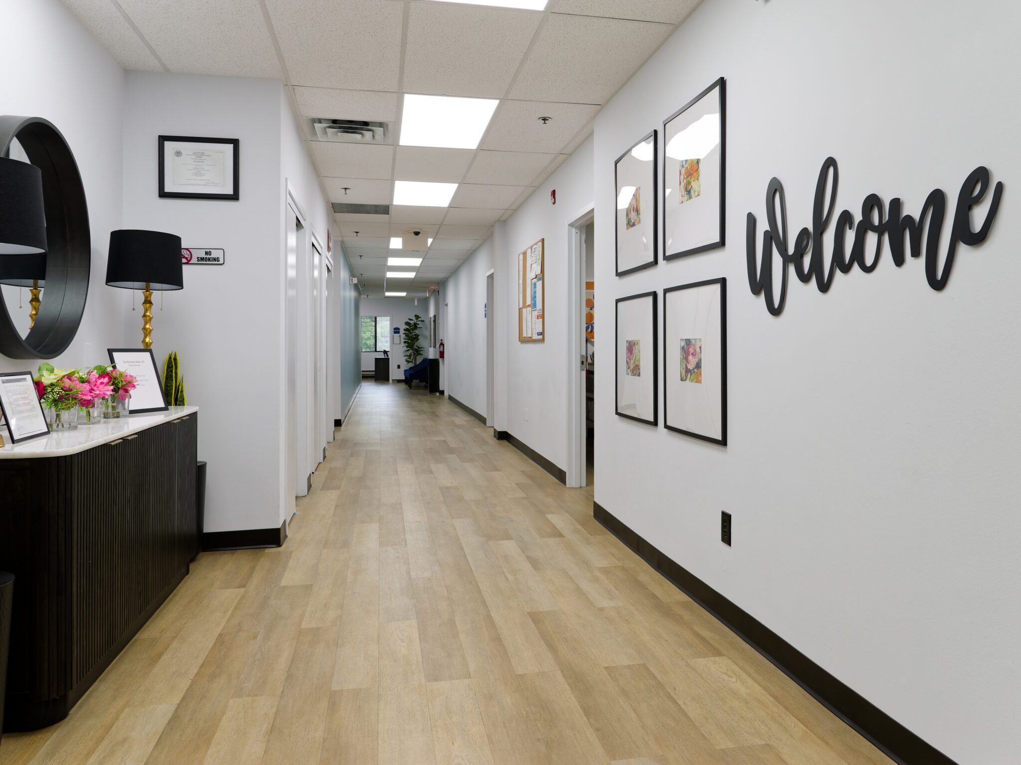 Hallway with welcome sign, framed artwork, and a small reception area.