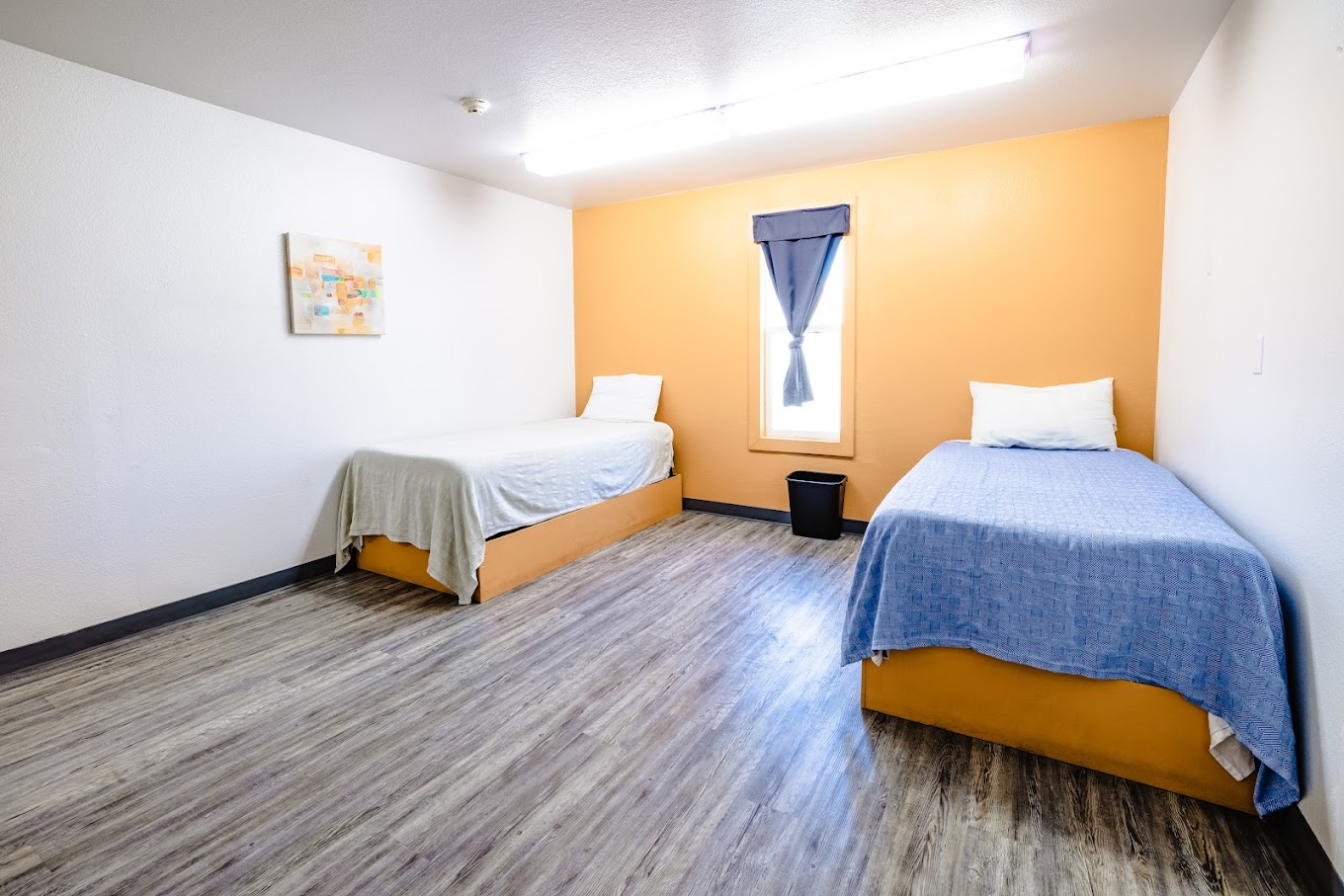 A shared bedroom with two twin beds and a yellow accent wall.