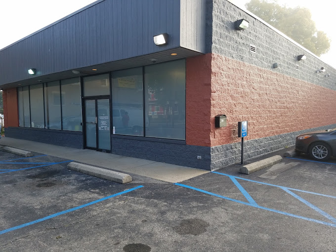 A waiting area with chairs, a bulletin board, and an open office door.