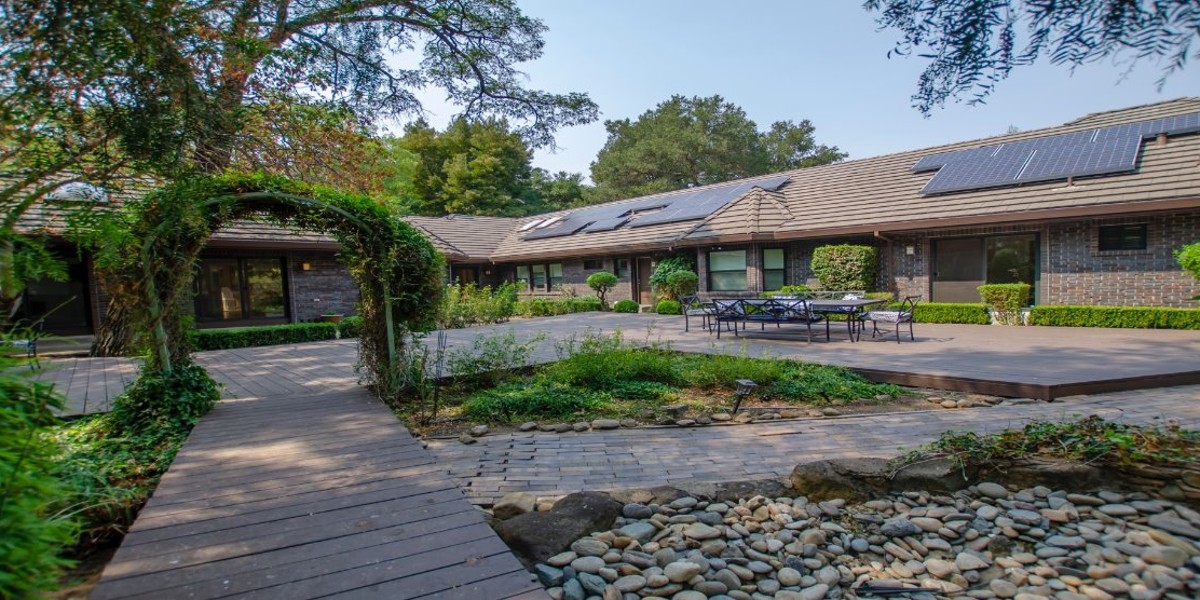 Courtyard with archway, patio seating, and landscaped garden