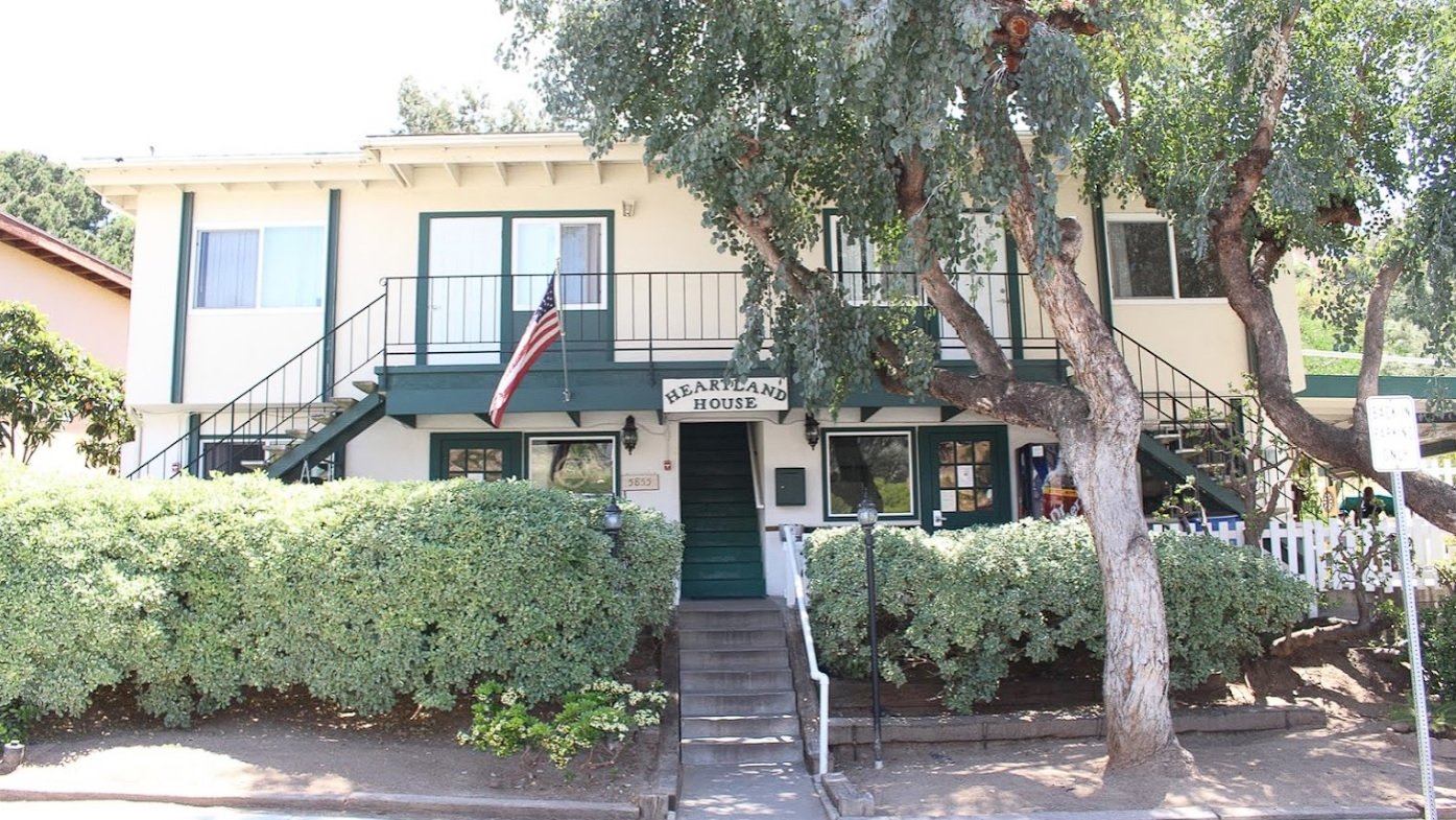 White two-story building with green trim and front staircase