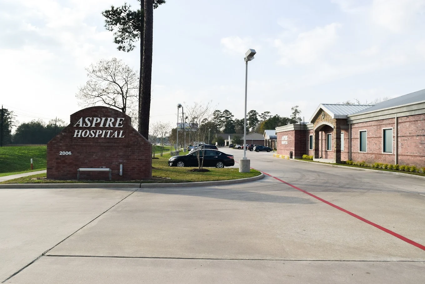 Brick hospital sign and facility exterior with parking