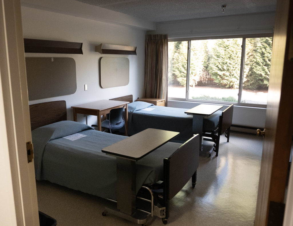 Shared bedroom with two beds, desks, and large window