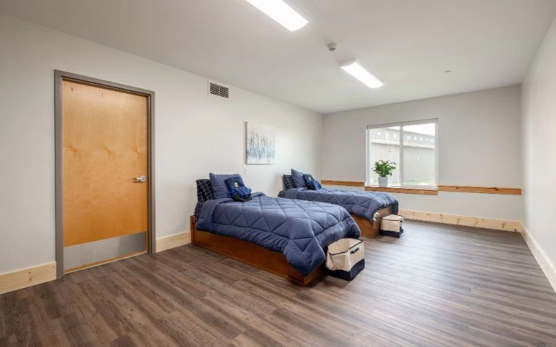 Two twin beds with navy bedding and wood floors
