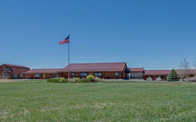 Large ranch-style facility with a red roof and American flag outside.