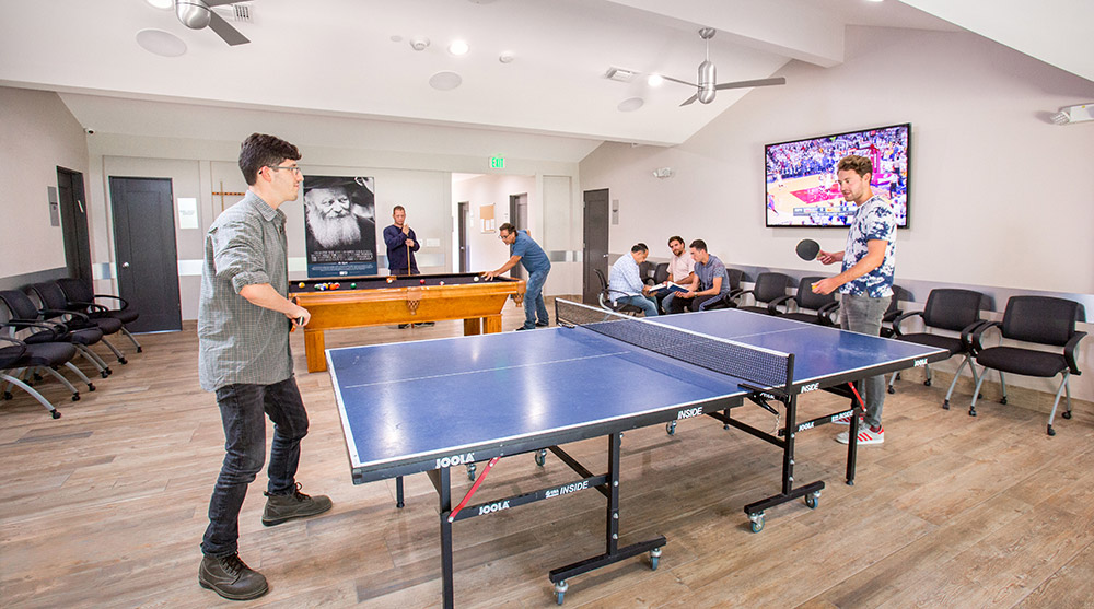 Recreation room with ping pong table, pool table, and TV at Chabad Treatment Center