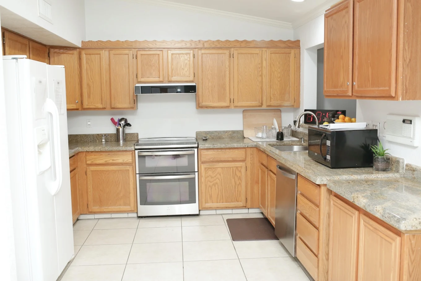 Functional kitchen with wood cabinetry, granite countertops, and white appliances in Scottsdale rehab center