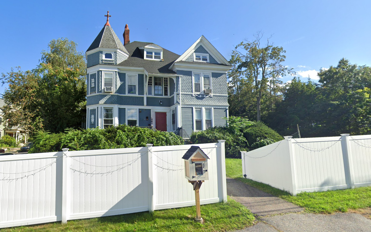 Blue Victorian-style home behind white fence
