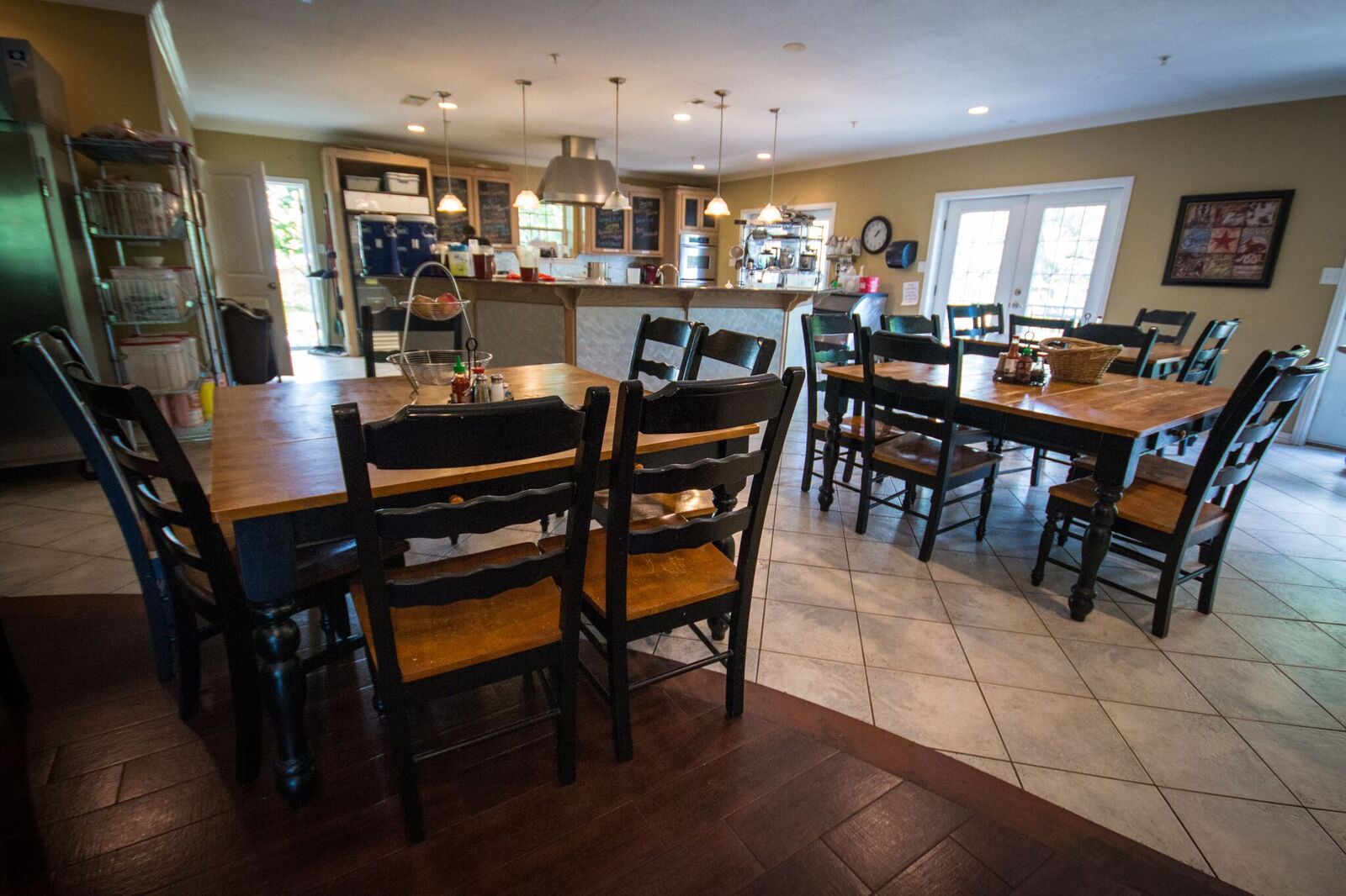 Wooden dining tables with chairs near open kitchen
