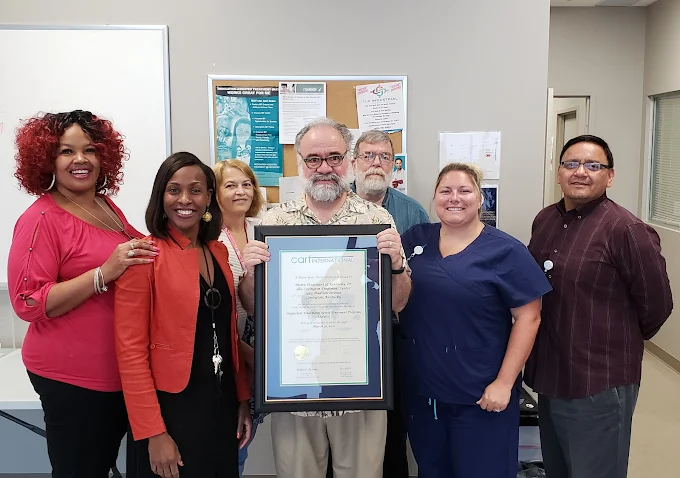 Staff group holding framed accreditation certificate