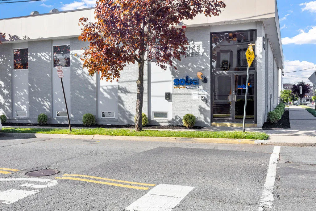 Street view of SOBA New Jersey’s white brick facility with signage and tree in front